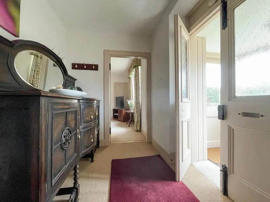 a hallway with a dresser and a mirror at Milton Cottages in Invercassley
