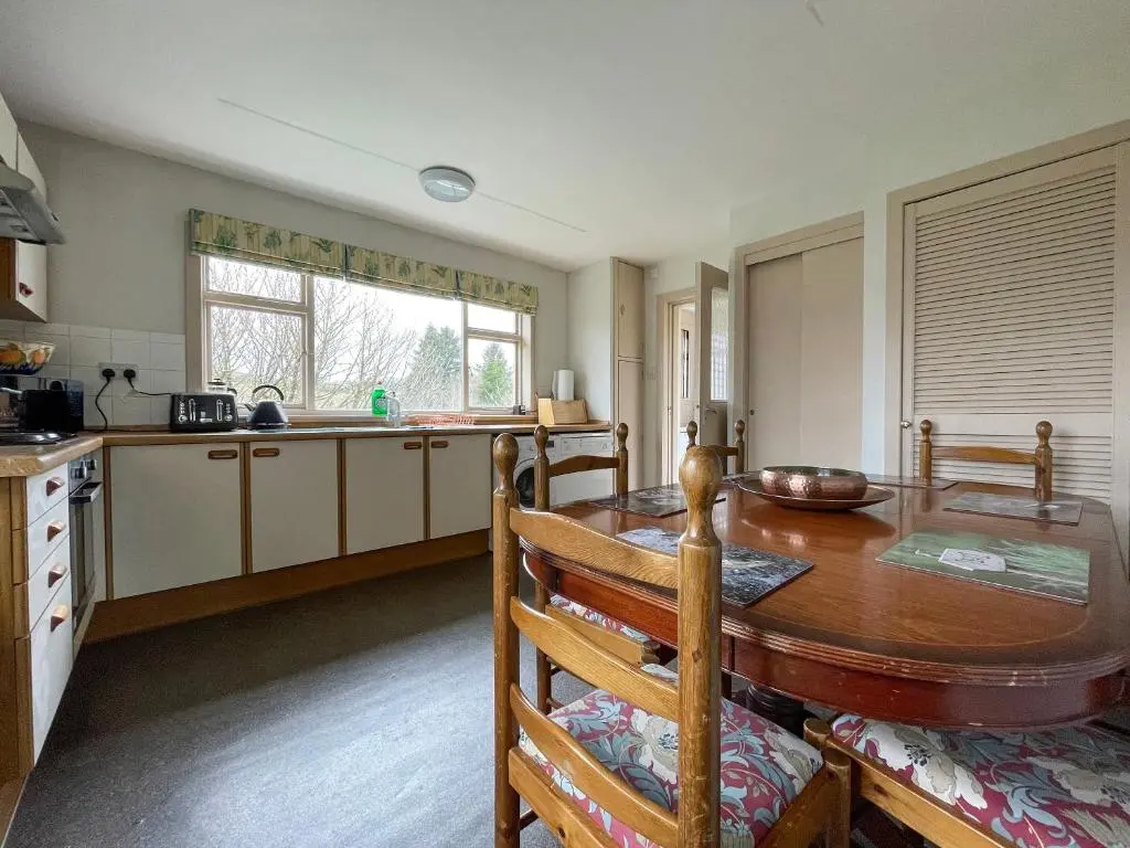 a kitchen with a wooden table and a dining room at Milton Cottages in Invercassley
