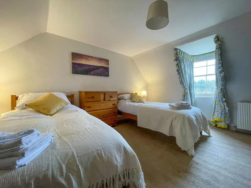 a bedroom with two beds and a window at Milton Cottages in Invercassley