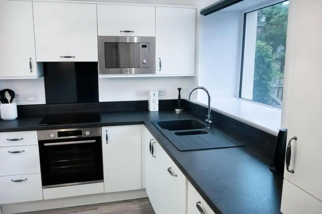 a kitchen with white cabinets and a sink and a microwave at Central 2 bedroom luxury home close to River Ness in Inverness