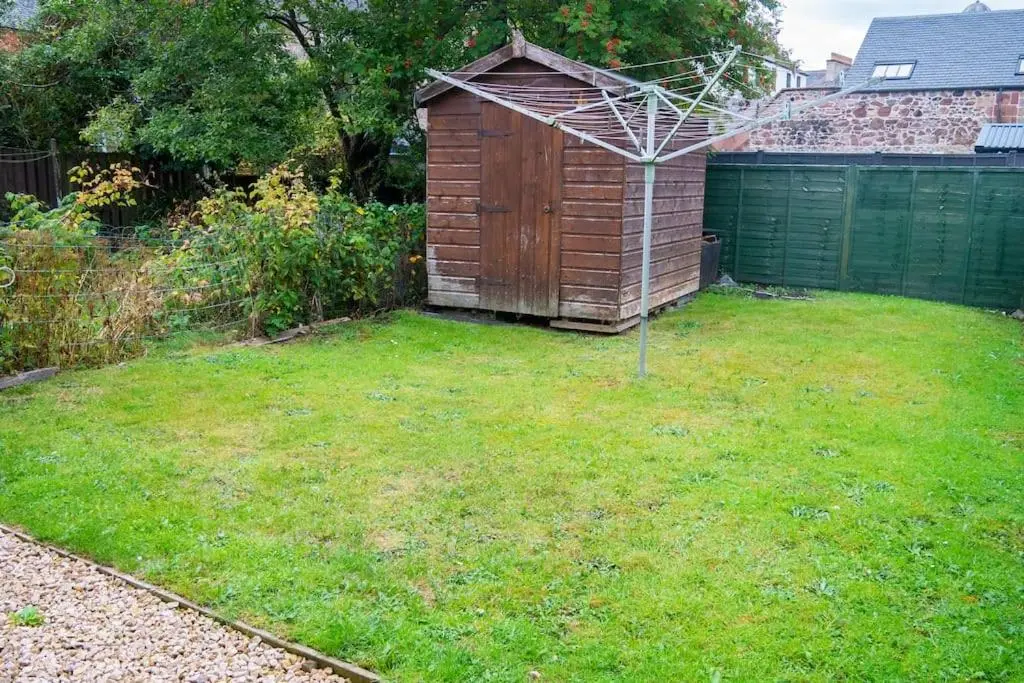 a backyard with a wooden shed in the grass at Central 2 bedroom luxury home close to River Ness in Inverness