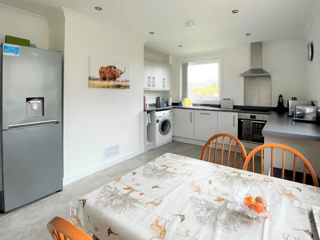 a kitchen with a table with chairs and a refrigerator at Westerdales in Fort Augustus