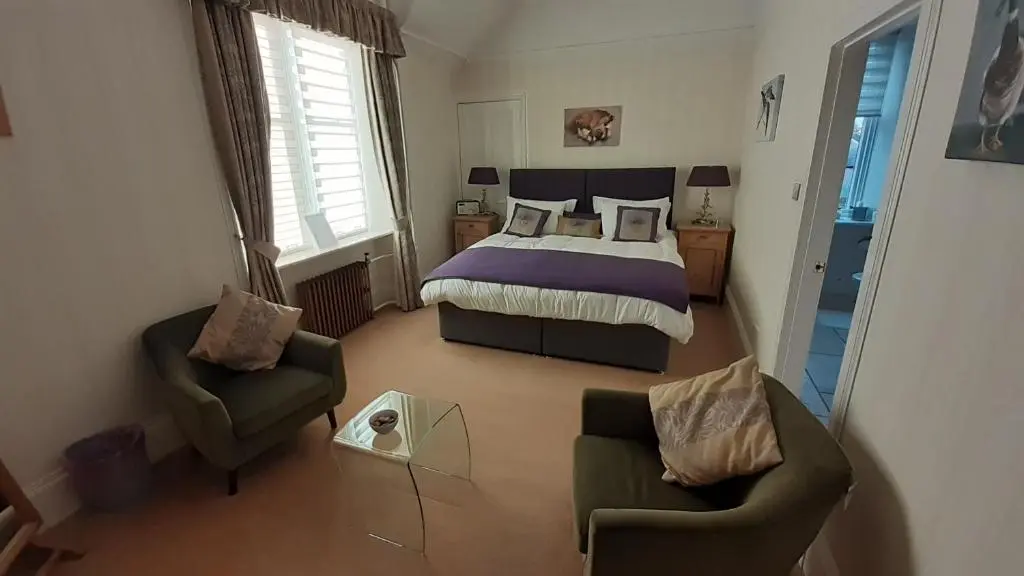 a bedroom with a bed and two chairs and a table at Trafford Bank Guest House in South Kessock