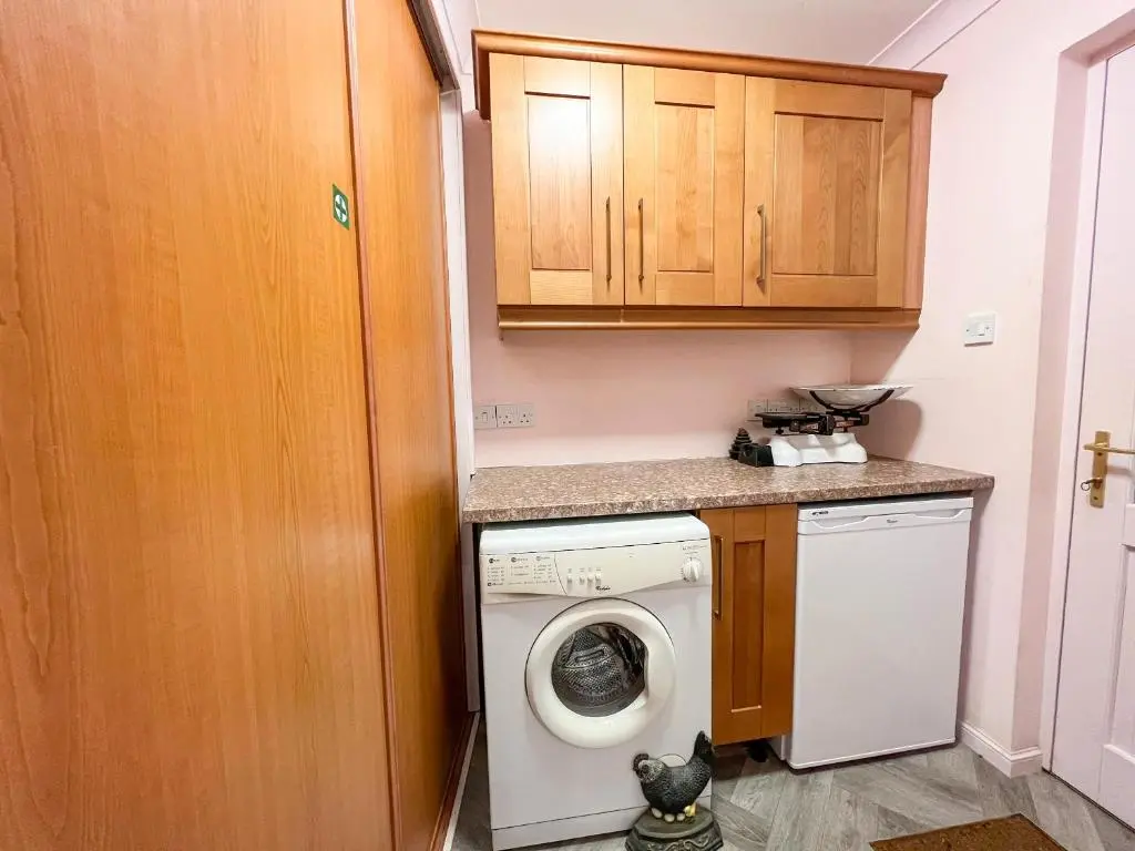 a laundry room with a washing machine and a washer at Creag Dhubh Cottage in Newtonmore