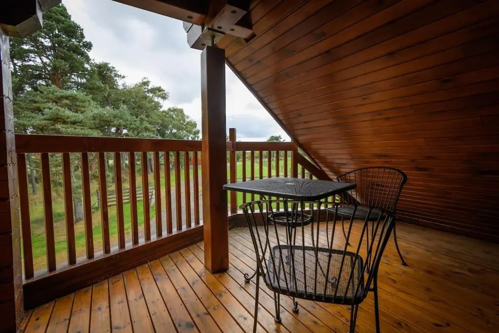a table and chairs sitting on a wooden deck at Norwegian Log Cabin The Roe Deer -sauna & hot tub in Keith