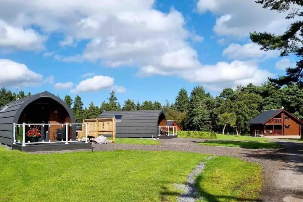 a farm with two barns and a grass field at Norwegian Log Cabin The Roe Deer -sauna & hot tub in Keith