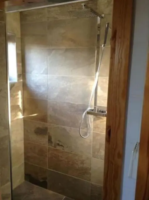 a shower with a glass door in a bathroom at Norwegian Log Cabin The Roe Deer -sauna & hot tub in Keith