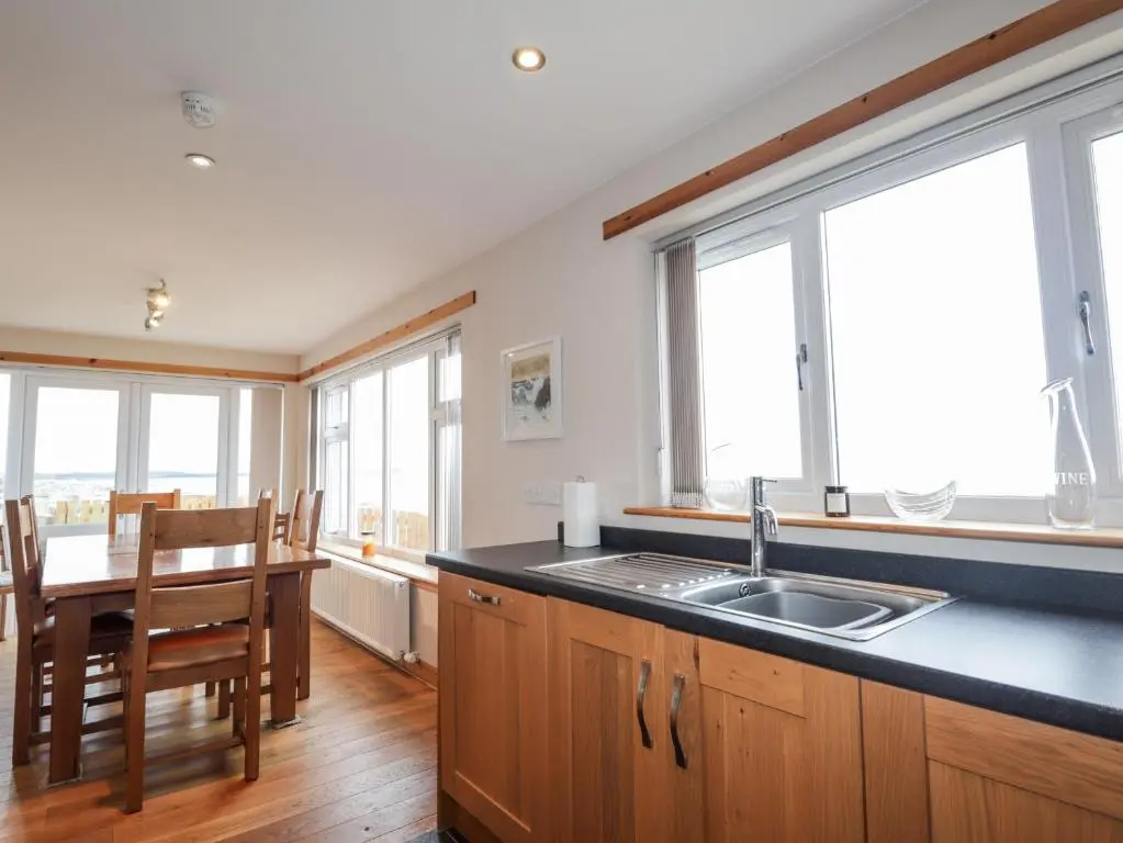 a kitchen with a sink and a table and windows at Learig in Buckie