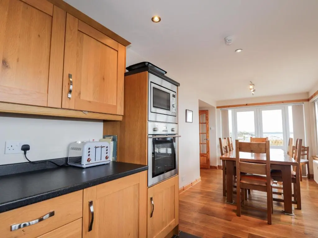 a kitchen with wooden cabinets and a dining room with a table at Learig in Buckie