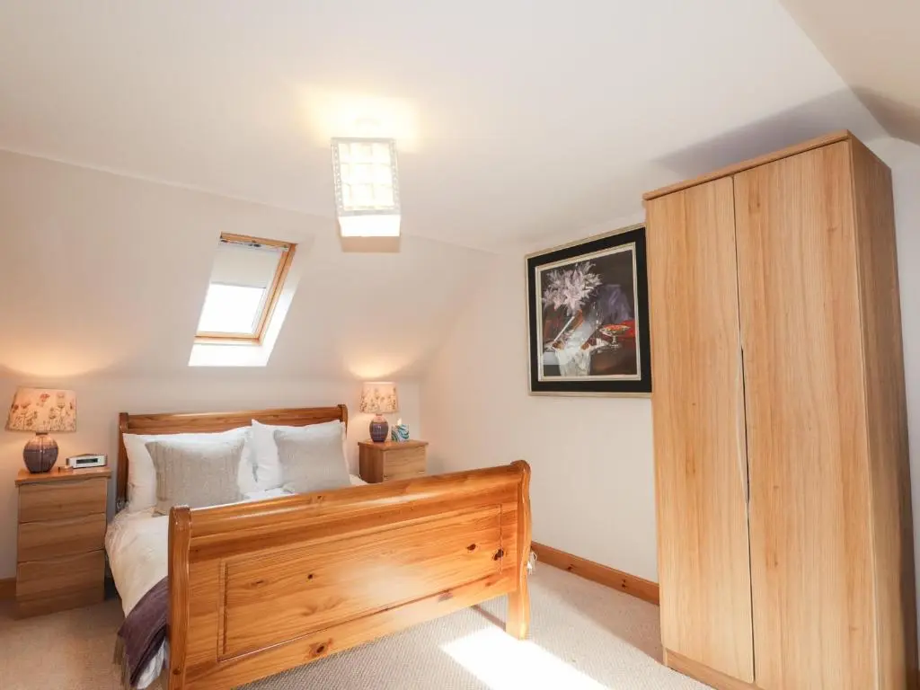 a bedroom with a wooden bed and a skylight at Learig in Buckie