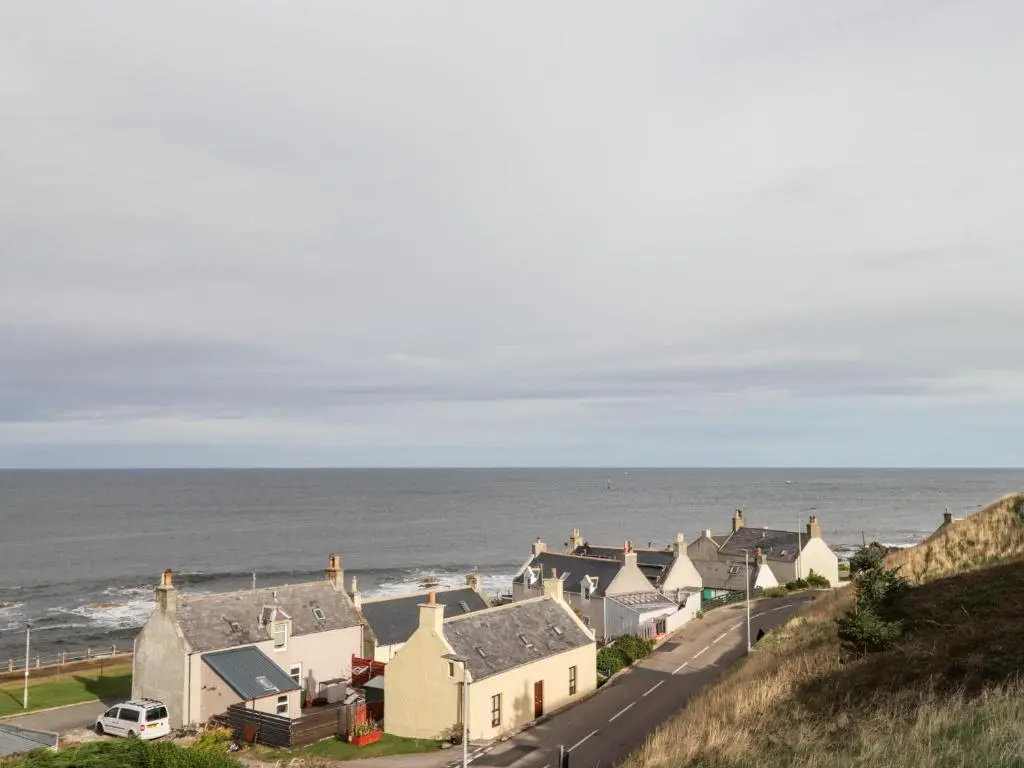 a row of houses on a hill next to the ocean at Learig in Buckie