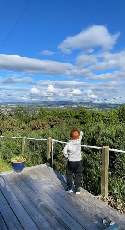 a person standing on top of a wooden deck at Woodside Cabin in Inverness