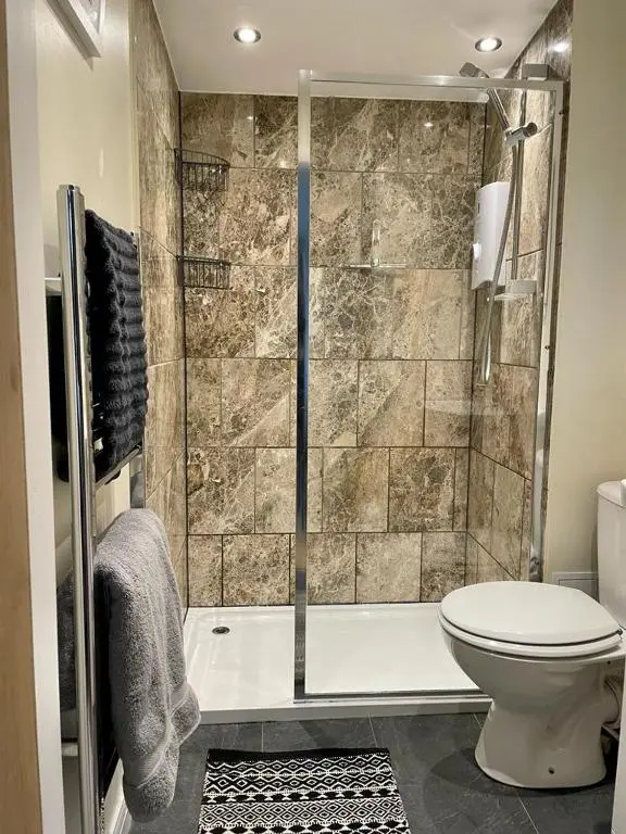 a bathroom with a shower and a toilet and a tub at Woodside Cabin in Inverness