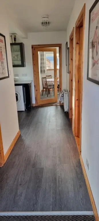 a living room with a wooden floor and a door at The Shelter Stone Cottage in Aviemore