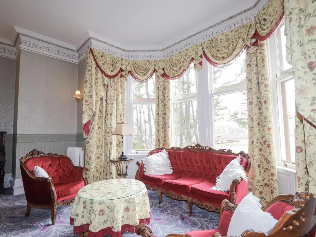 a living room with red couches and a window at Ledgowan Lodge Hotel in Achnasheen