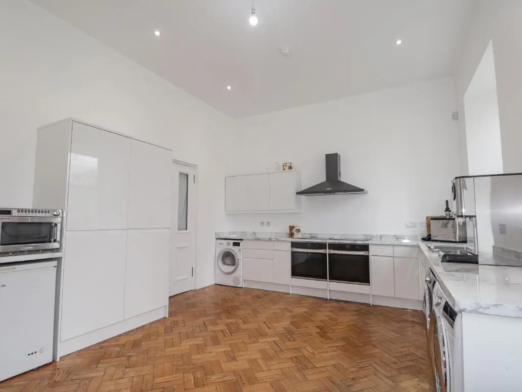 a white kitchen with white cabinets and a wooden floor at Ledgowan Lodge Hotel in Achnasheen
