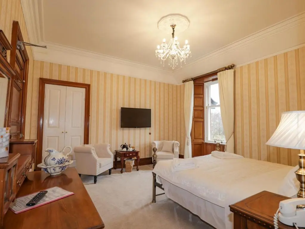 a bedroom with a bed and a table and a television at Ledgowan Lodge Hotel in Achnasheen