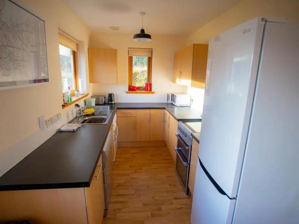 a kitchen with a white refrigerator and a sink at Holiday Home Peter's Shed by Interhome in Drumnadrochit