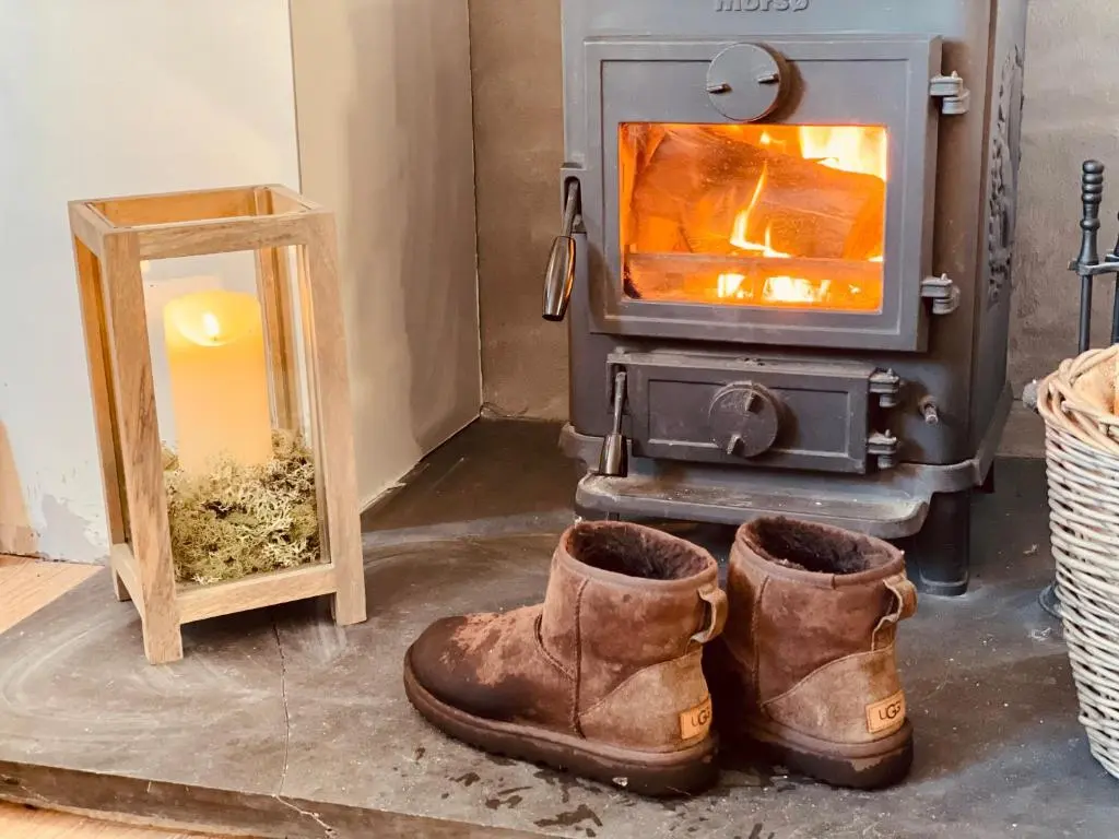 a pair of boots in front of a wood stove at Stag's Hide in Aviemore