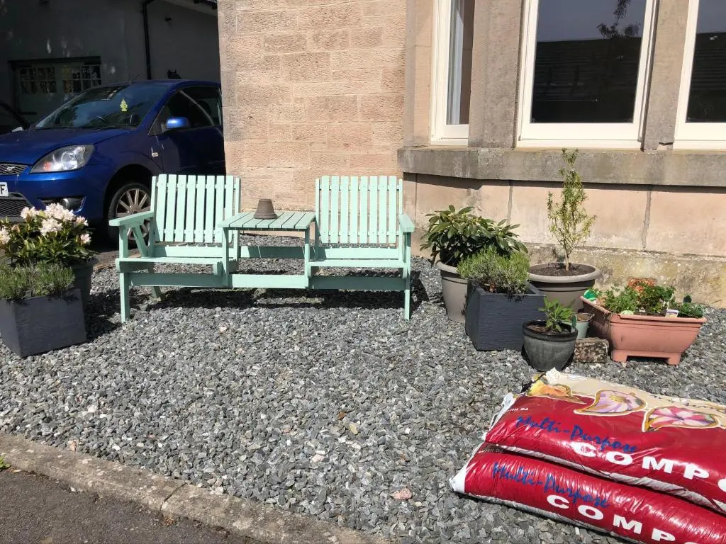 two chairs and a table and potted plants in front of a building at Corsee House in Nairn