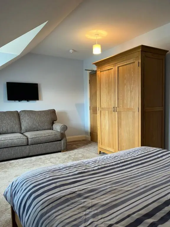 a bedroom with a bed and a couch and a tv at Corsee House in Nairn