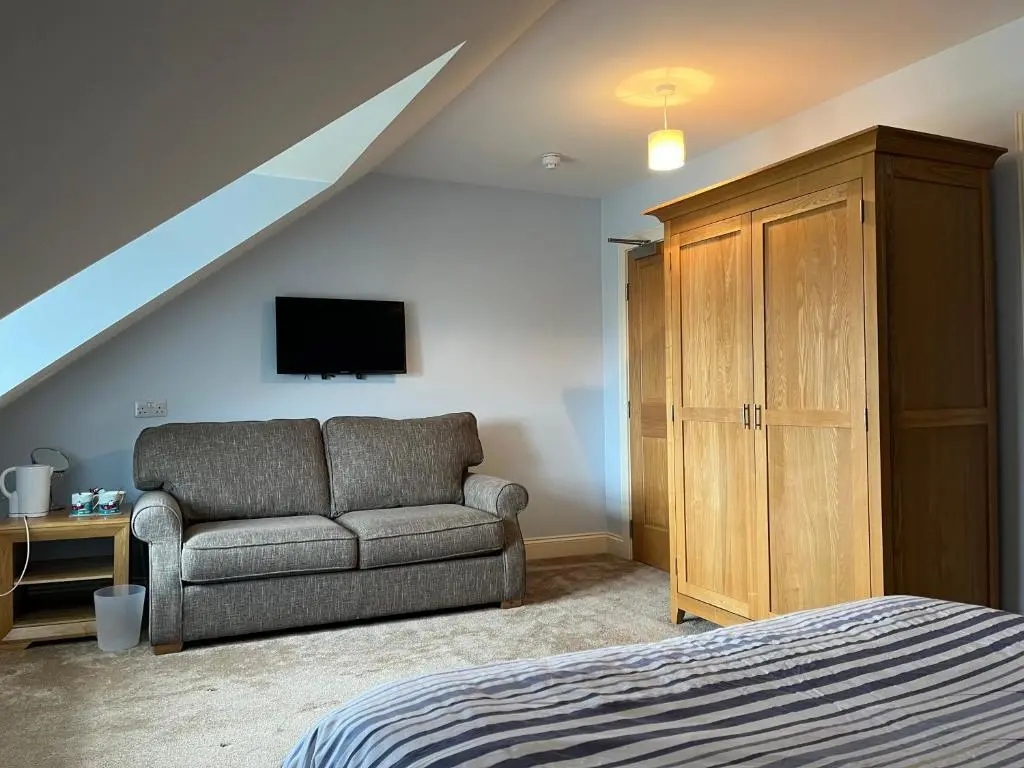 a bedroom with a bed and a couch and a tv at Corsee House in Nairn