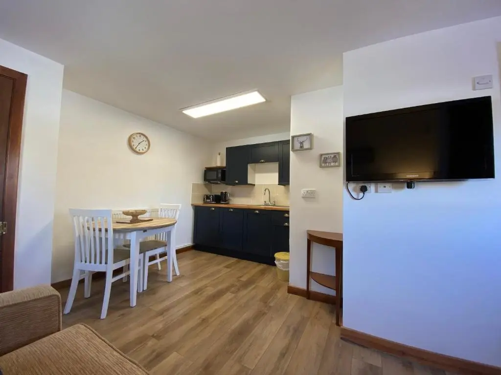 a living room with a kitchen and a table with chairs at Ben View Aberlour Luxury Barn Conversion in Aberlour