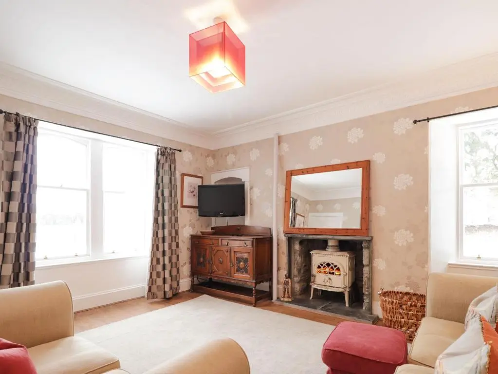 a living room with a fireplace and a tv at The Larches in Kingussie