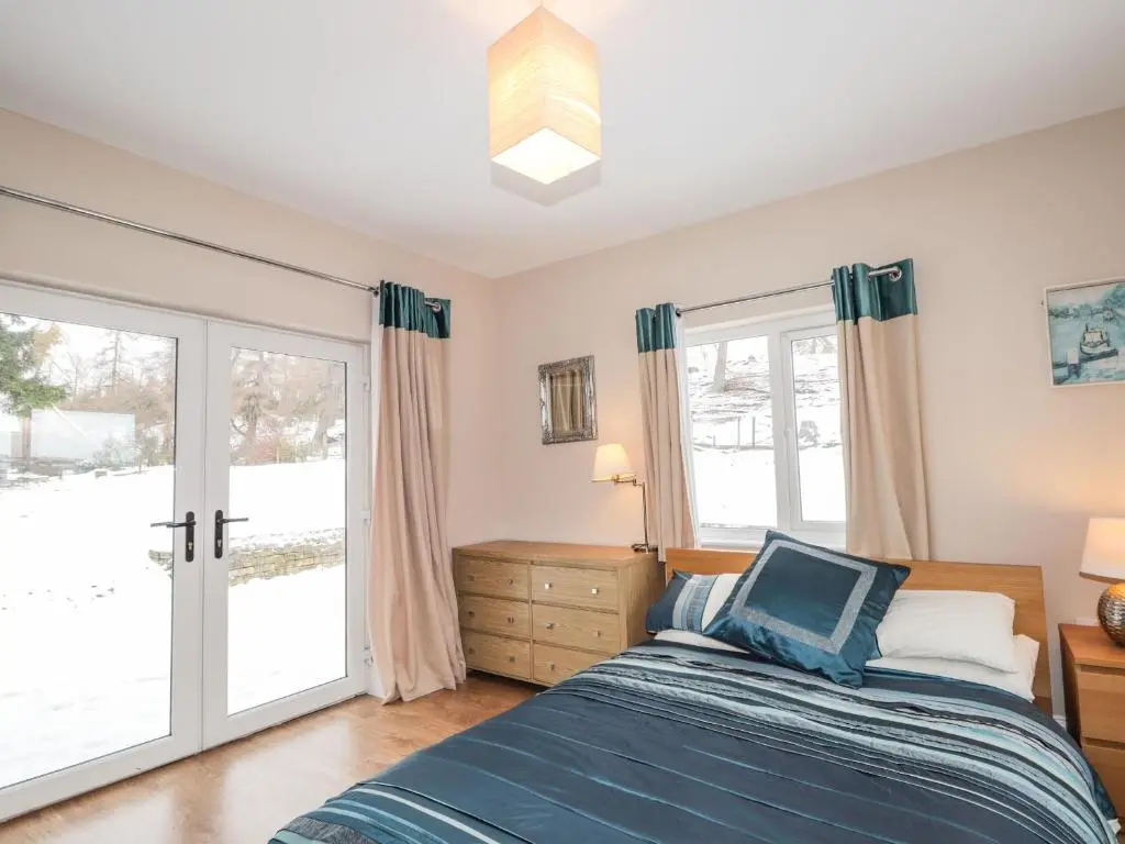 a bedroom with a bed and sliding glass doors at The Larches in Kingussie