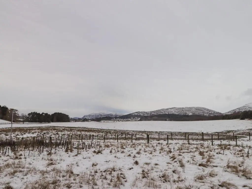 a field covered in snow with a fence at The Larches in Kingussie