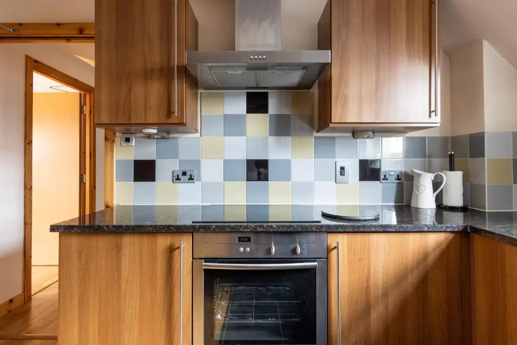 a kitchen with wooden cabinets and an oven at The Rooftops Reservation in Inverness
