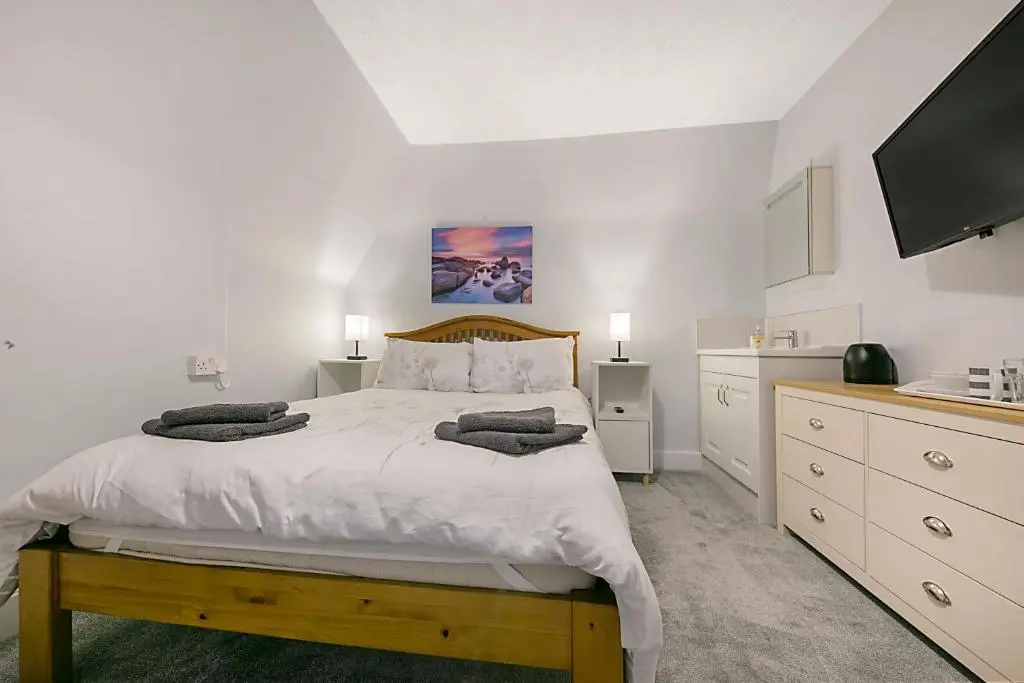 a white bedroom with a large bed and a flat screen tv at Constancevilla B9 - Grampian Lettings Ltd in Aberdeen