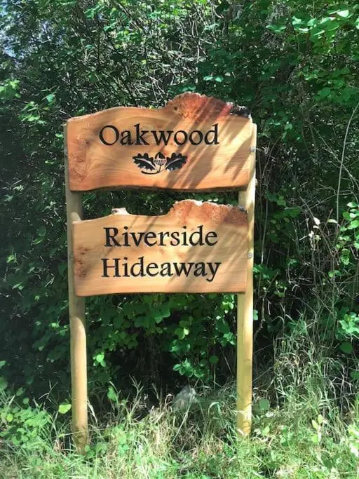a wooden sign in the middle of a field at Riverside Hideaway in Kincraig