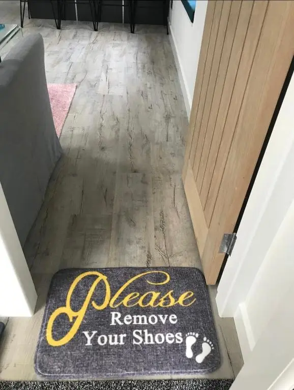 a welcome rug on the floor in front of a door at Riverside Hideaway in Kincraig