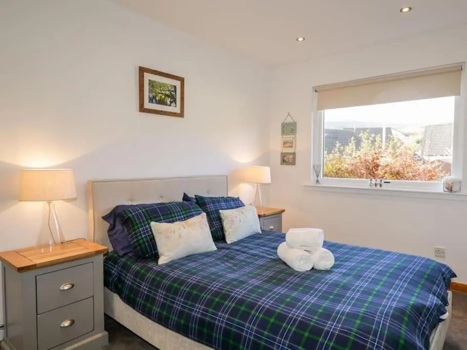 a bedroom with a bed with a teddy bear on it at Stewart's Cottage, Aviemore Centre in Aviemore