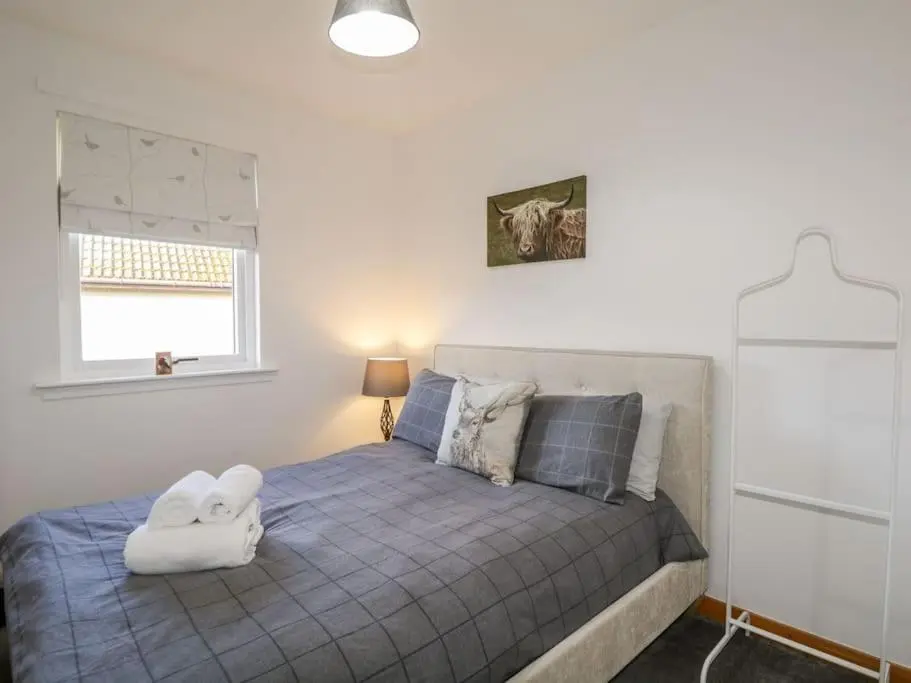 a bedroom with a bed with a pillow on it at Stewart's Cottage, Aviemore Centre in Aviemore