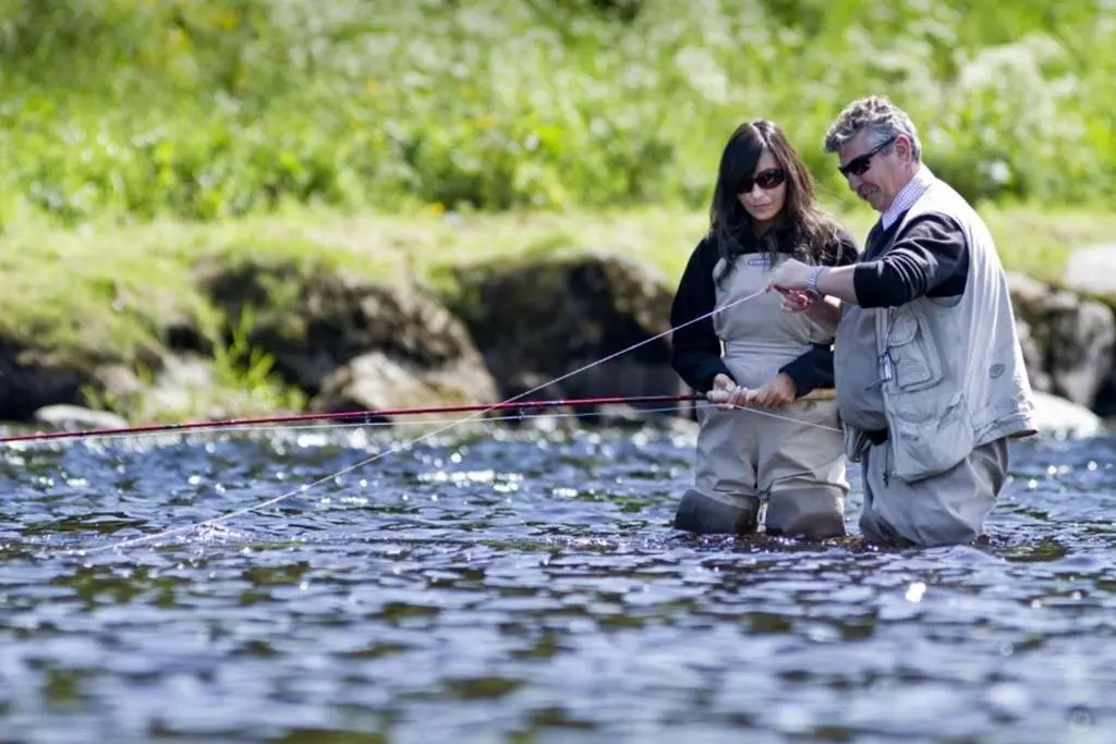 a man and a woman standing in the water fishing at Stewart's Cottage, Aviemore Centre in Aviemore