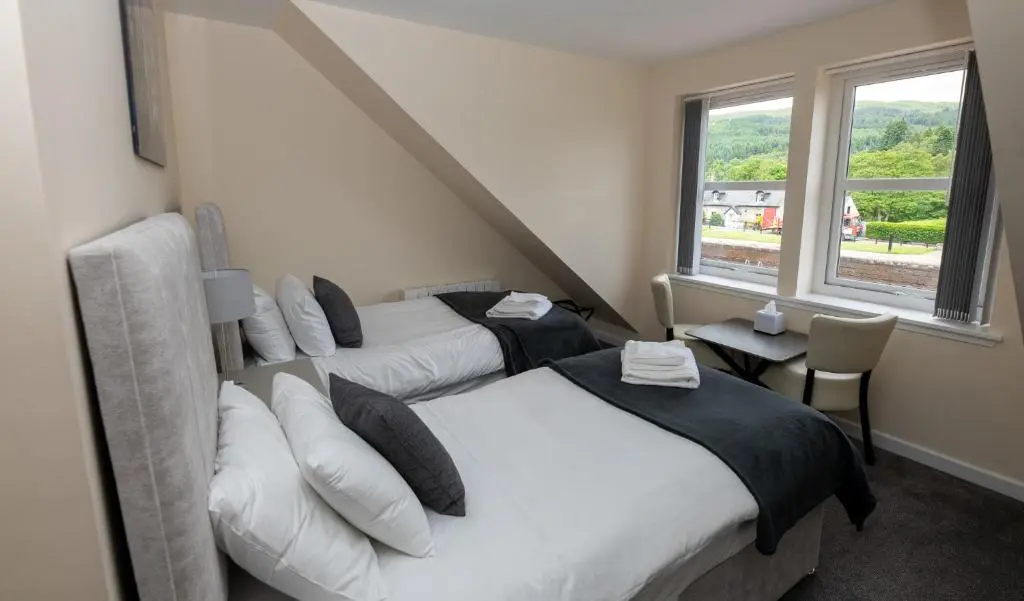 a bedroom with two beds and a window at Loch Ness Gate House in Fort Augustus