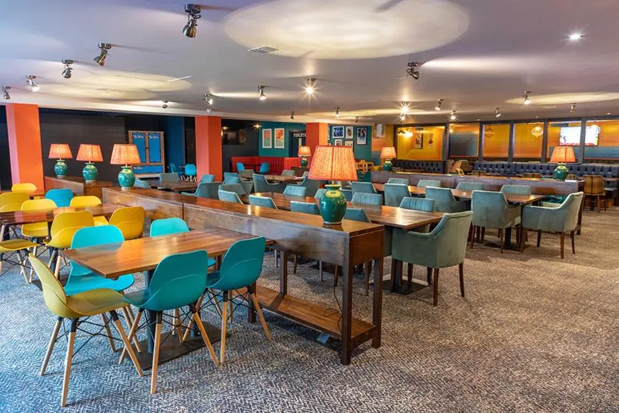 a cafeteria with tables and chairs in a room at Camping Pods Silver Sands Holiday Park in Lossiemouth