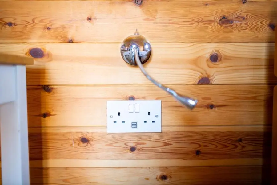 a light switch on a wooden wall with a socket at Camping Pods Silver Sands Holiday Park in Lossiemouth