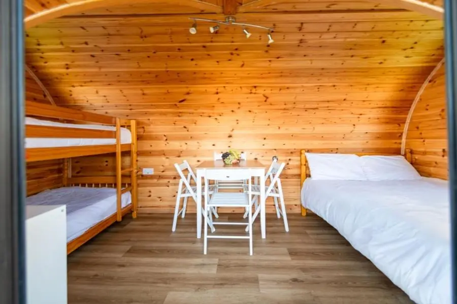 a room with two beds and a table and chairs at Camping Pods Silver Sands Holiday Park in Lossiemouth