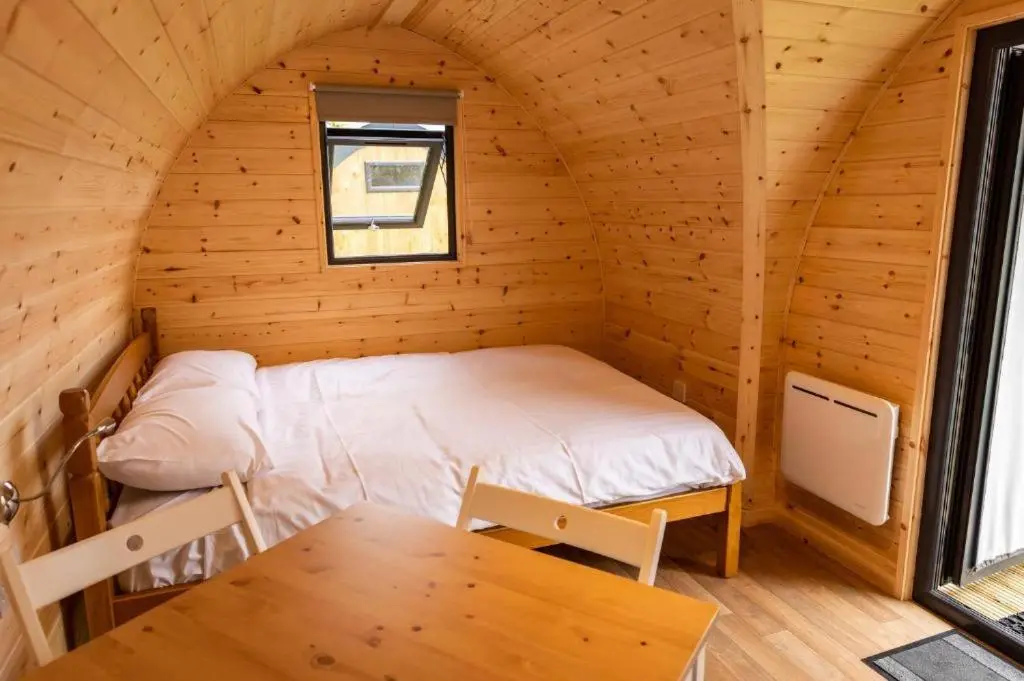 a bedroom in a log cabin with a bed and a table at Camping Pods Silver Sands Holiday Park in Lossiemouth