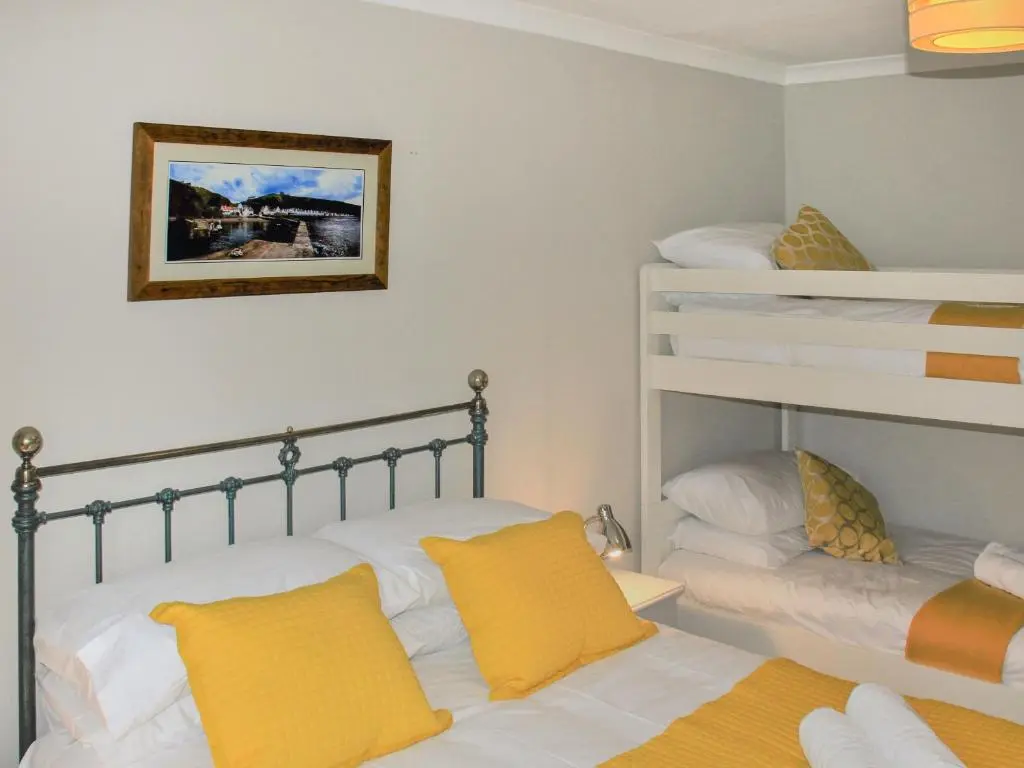 a bedroom with two bunk beds with yellow pillows at Harbour Road in Gardenstown