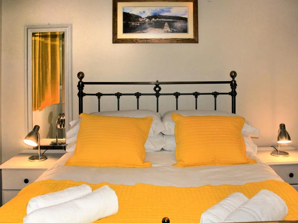 a bedroom with a bed with two orange pillows at Harbour Road in Gardenstown