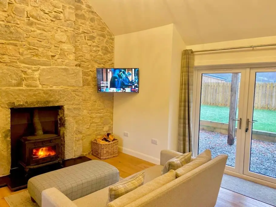 a living room with a stone fireplace and a tv at The Old Croft in Fort Augustus