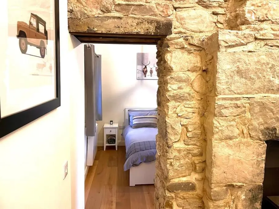 a bedroom with a bed and a stone wall at The Old Croft in Fort Augustus