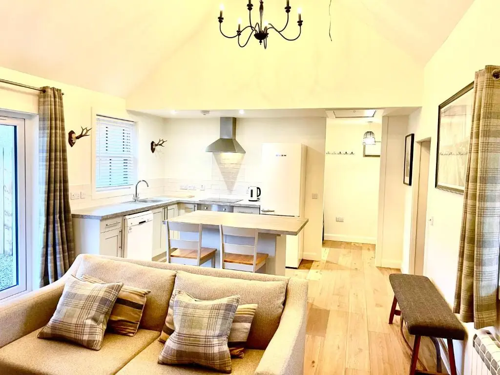 a living room with a couch and a kitchen at The Old Croft in Fort Augustus
