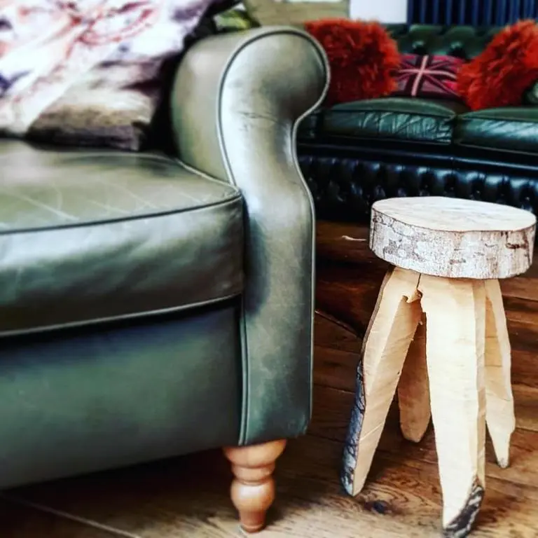 a green leather couch with a table next to a couch at Baltinna East - by Where Stags Roar in Newtonmore