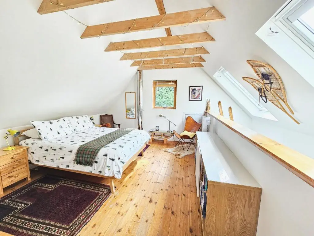 a bedroom with a bed and a staircase at Baltinna East - by Where Stags Roar in Newtonmore