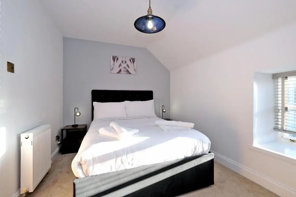 a bedroom with a bed with white sheets and a window at Rosebrae in Insch